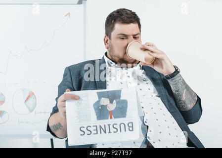 Fat Man de boire du café et de la lecture de journaux d'affaires in office Banque D'Images