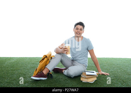 Teenage student garçon assis sur l'herbe avec du café pour aller isolated on white Banque D'Images