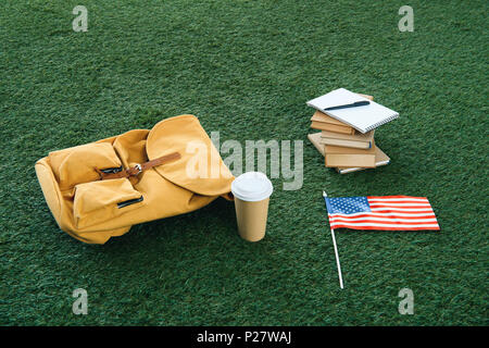 Vintage sac à dos jaune et des fournitures scolaires aux usa flag on Green grass Banque D'Images
