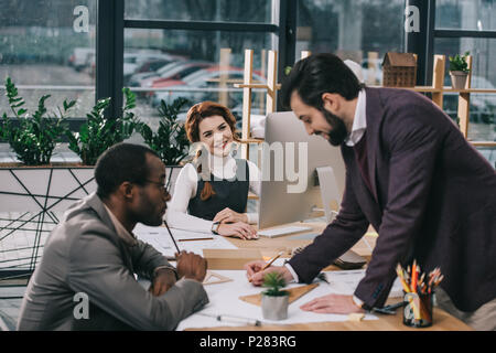 Architectes multiethnique discussing blueprints in modern office Banque D'Images