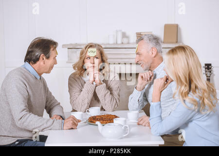 Amis jouant des jeux de cartes avec des mots sur les épaules, alors que sitting at table Banque D'Images