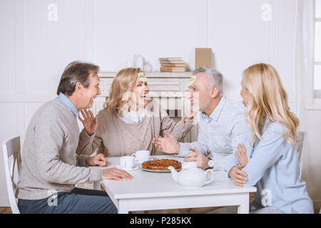 Amis jouant des jeux de cartes avec des mots sur les épaules, alors que sitting at table Banque D'Images