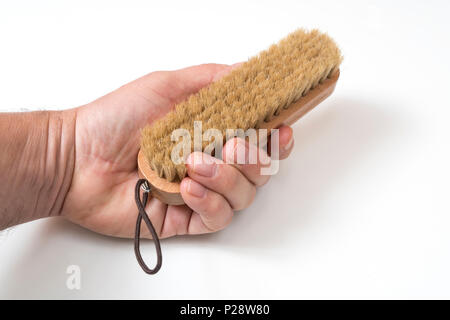 Une brosse à vêtements dans la main sur une surface blanche Banque D'Images