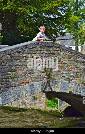 Un jeune garçon se penche sur le bord de l'observation des bateaux pont Bonifacius passer en dessous. Bruges ou Brugge, Belgique Banque D'Images