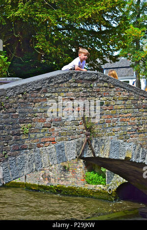 Un jeune garçon se penche sur le bord de l'observation des bateaux pont Bonifacius passer en dessous. Bruges ou Brugge, Belgique Banque D'Images