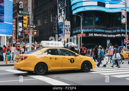 Taxi jaune en attente sur le feu à New York, les piétons qui traversent en face d'elle. Banque D'Images