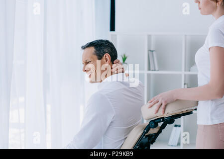 Businessman avec douleur dans le cou en séance de bureau masseuse Banque D'Images