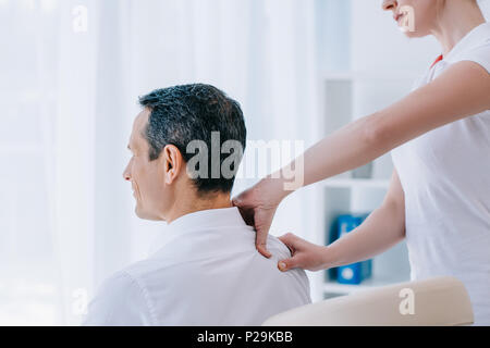 Faire masseuse massage épaule assis pour l'homme d'affaires Banque D'Images