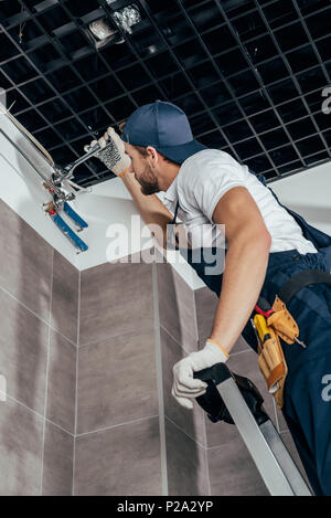 Low angle view of plumber standing et de travail avec des tuyaux dans la salle de bains Banque D'Images