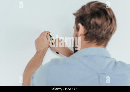 Vue arrière de l'aide d'une pince et contremaître jeunes décollant d'un mur d'ongle Banque D'Images