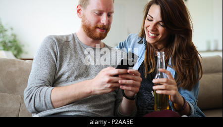 Cheerful couple laughing regardant smart phone Banque D'Images