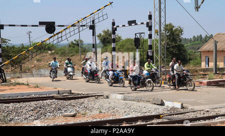 Shrirangapattan, Inde - 2 mars 2018 : motocyclistes sur un passage à niveau à l'extérieur de la gare de Srirangapatnam immédiatement après qu'un train est passé Banque D'Images