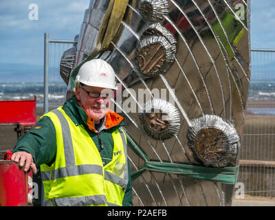 Musselburgh, East Lothian, Ecosse, Royaume-Uni, le 14 juin 2018. L'installation de sculpture par Michael Johnson, qui ses boulons en acier inoxydable de 2 tonnes sculpture 'Mémoire et réflexion" en place dans Murdoch vert. La coquille des moules en bronze poli à la main sculpture a cartouches représentant l'histoire de la ville et mesure 14 m de haut par 6 pieds de large. Conçu et construit par la Bretagne, sculpteur, il est commandé par l'East Lothian Council dans le cadre de sa politique des arts de pour cent et financé par Tesco. Le sculpteur a lutté avec Hector tempête Vent comme il a été placé. L'installation du sculpteur sculpture Banque D'Images