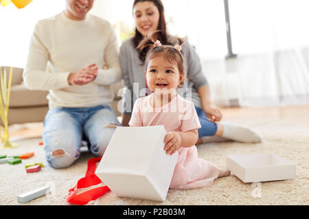 Baby Girl avec le cadeau d'anniversaire et les parents à la maison Banque D'Images