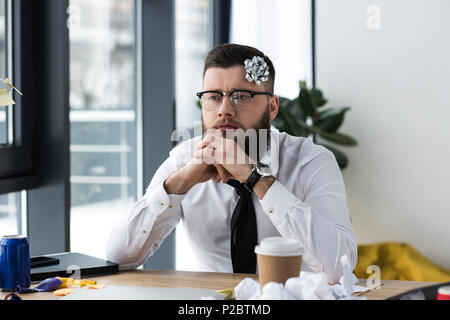 Portrait of pensive businessman avec noeud sur la tête à au travail Banque D'Images