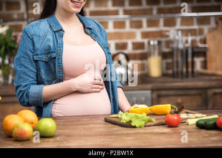 Cropped shot of young pregnant woman touching belly pendant la cuisson Banque D'Images