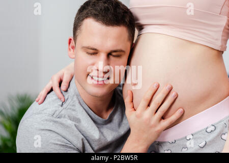 Cropped shot of happy man listening au ventre de femme enceinte Banque D'Images