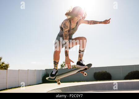 Les femmes pratiquant le skate skater à skate park. Les femmes faisant ollie sur planche. Banque D'Images