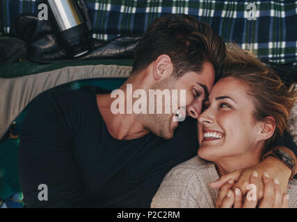 Vue de dessus pour couple romantique à l'intérieur d'une tente. Smiling man and woman lying together et se regardant dans une tente. Banque D'Images