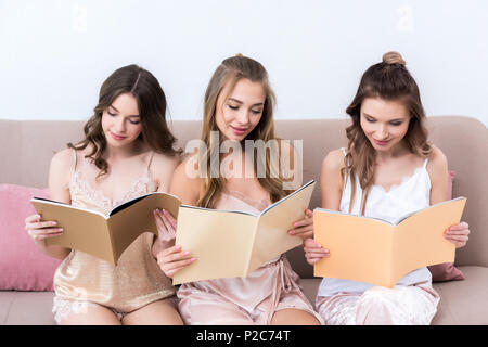 Belles jeunes femmes en pyjama la lecture de revues à la maison Banque D'Images