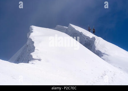 Une femelle et un mâle mountaineer transportant leurs skis de randonnée sur leurs sacs à dos et de la montée d'une pente de neige raide, à côté d'eux bi Banque D'Images