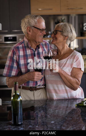 Senior couple toasting verres de vin dans la cuisine Banque D'Images