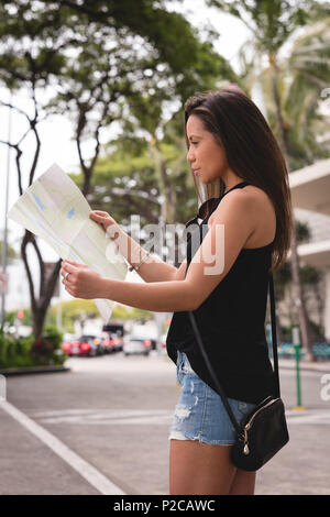 Woman looking at map in city street Banque D'Images