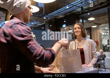 Vendeur de sacs en papier et de donner de l'argent à woman at cafe Banque D'Images