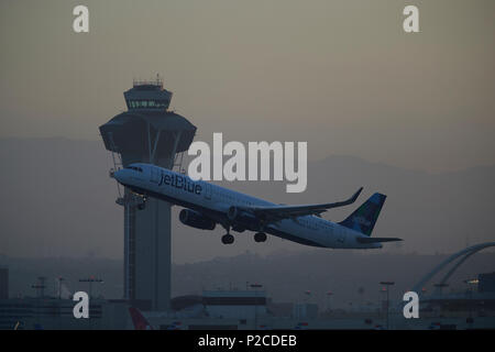 JetBlue Airbus A321 avion de décoller de l'Aéroport International de Los Angeles, LAX, au lever du soleil, la tour de contrôle et les montagnes San Gabriel derrière. Banque D'Images