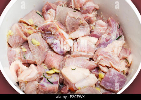 La viande de porc cru assaisonné sur un bol. Porc assaisonné de sel, l'ail et le romarin. La préparation des pièces de porc avant de fry. Banque D'Images
