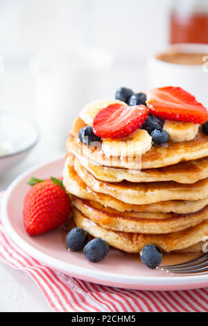 Pile de crêpes maison avec des fraises, banane et les mûres sur une plaque rose Banque D'Images