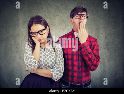 Homme et femme sur la date à la fois désintéressée et terne debout sur fond gris. Banque D'Images