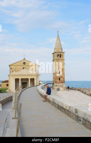 L'homme sur un mur près d'une église, Madonna dell' Angelo, Caorle, Région Vénétie, Adriatique, Italie, Europe Banque D'Images