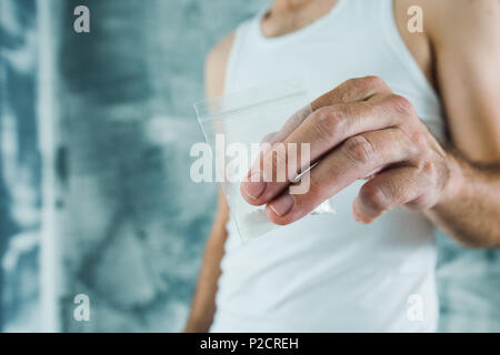 Membre de gangs et de drogues offrant du crack dans un petit sachet plastique, Close up of hands with selective focus Banque D'Images