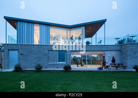 Vue extérieure de la façade est au crépuscule. Tennis Loisirs Canoe Lake Pavilion, Southsea, Royaume-Uni. Architecte : PAD Studio, 2017. Banque D'Images