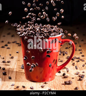 Big Red Espresso tasse sur une table en bois avec les grains de café tomber à l'intérieur Banque D'Images