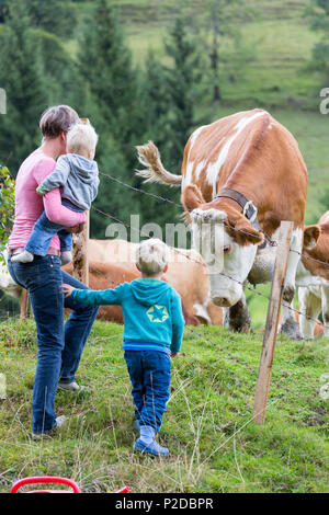 Famille, de la mère et de deux enfants debout devant une prairie alpine, les vaches avec cowbell, M., Maria Alm, Berchtesgadener Land, un Banque D'Images