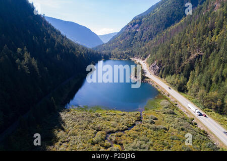 Lac et une route au milieu des montagnes couvertes de forêts Banque D'Images