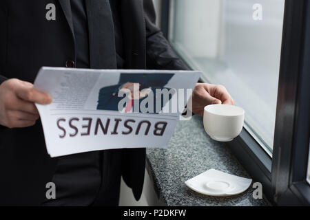 Vue partielle de businessman reading newspaper et holding Coffee cup Banque D'Images
