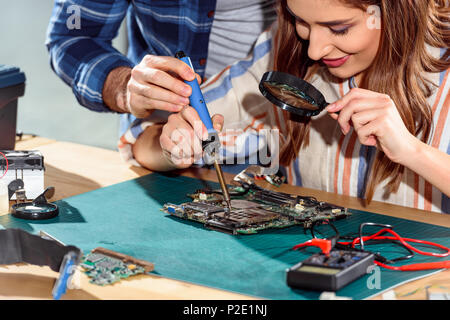 Man helping woman soudage des éléments de circuit board