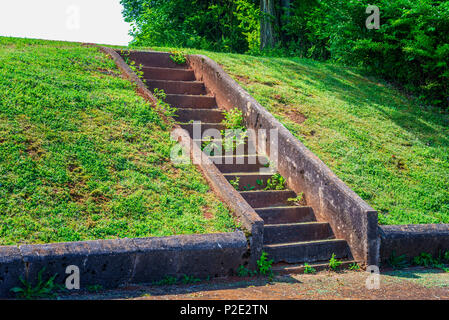 Ancien des mesures concrètes qui monte une colline d'herbe verte. Banque D'Images