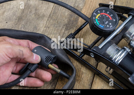 Pompe à pied et vélo sur un tube de Workbench. Accessoires pour pneus de vélos et de réparation. Fond sombre. Banque D'Images