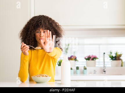 African American Woman eating les céréales et le lait à la maison avec main ouverte faisant stop avec de sérieux et de confiance, l'expression gestuelle de la défense Banque D'Images