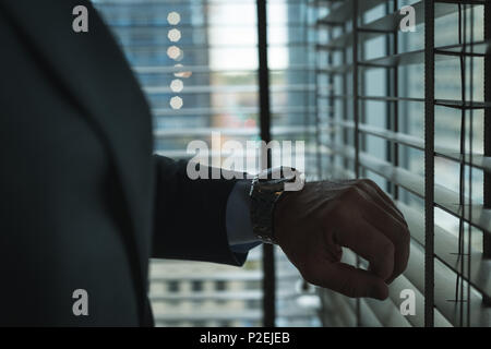 Businessman checking time on wrist watch Banque D'Images