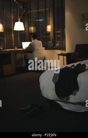 Businessman using laptop in bedroom Banque D'Images