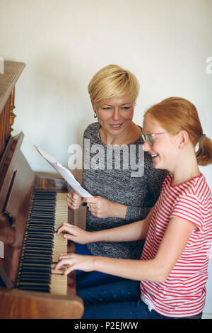 Aider la mère-fille à jouer du piano à la maison Banque D'Images