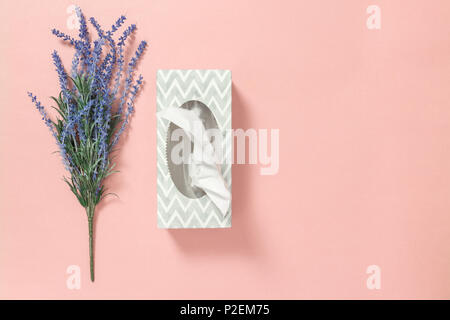 Boîte de tissus gris et bleu lavande sur fond rose pastel. Banque D'Images