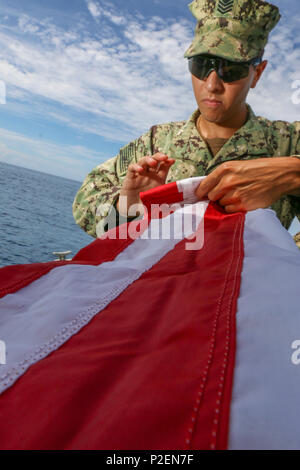 Les gardes côte affecté à la Force opérationnelle Guantanamo plie un drapeau des États-Unis après le vol pour 9 minutes et 11 secondes en cours sur un bateau de sécurité portuaire transportable, le 11 septembre sur la base navale américaine de Guantanamo, à Cuba. Le Coasties LA FOI Troopers offert la possibilité de présenter leur drapeau de l'avoir volé dans la zone de fonctionnement de l'honneur de commémorer la journée qui a secoué notre pays. (Photo prise par le sergent de l'armée américaine. Sarah Kirby // libéré) Banque D'Images