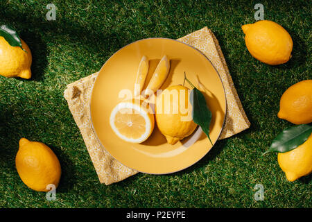 Vue du haut de la plaque avec les citrons et les tranches de citron sur pelouse verte Banque D'Images