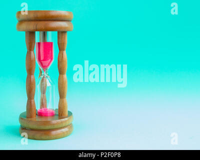 Hourglass Vintage en bois avec sable rose sur fond bleu, sable fonctionnant par les ampoules pour mesurer le temps qui passe dans un compte à rebours jusqu'à échéance. Banque D'Images